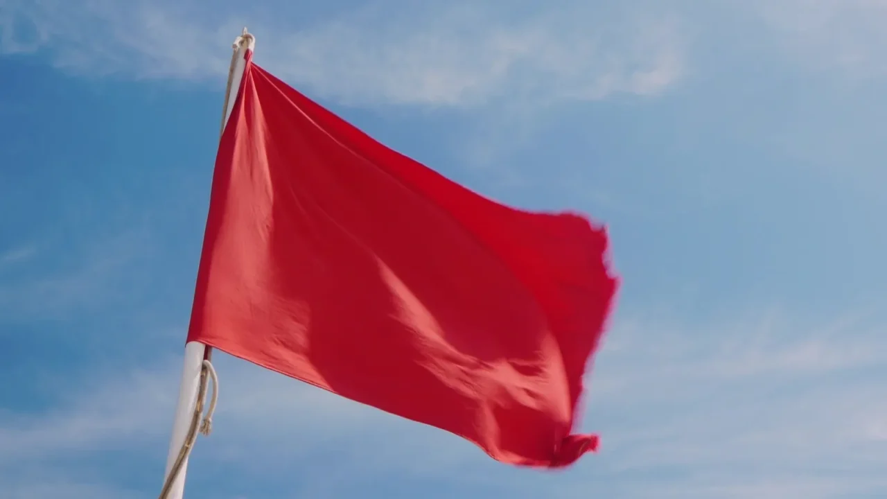red flag on a background of blue sky dangerous for
