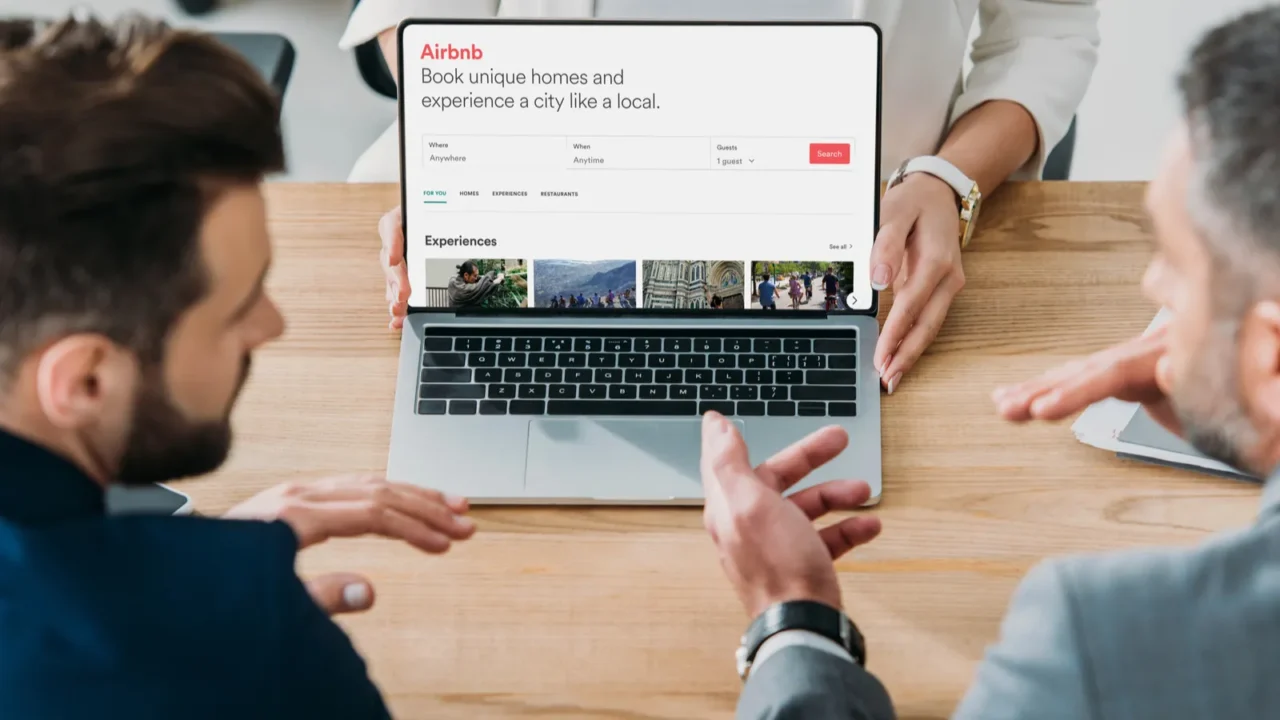 selective focus of advisor showing to investors laptop with airbnb