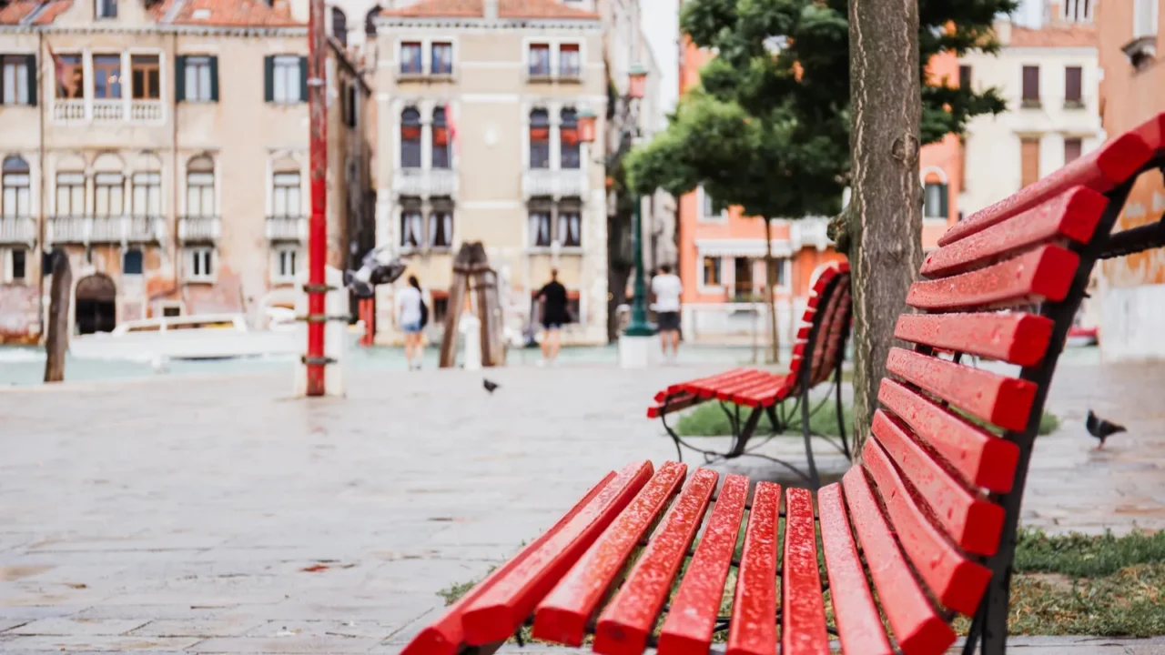selective focus of red bench and ancient buildings on background