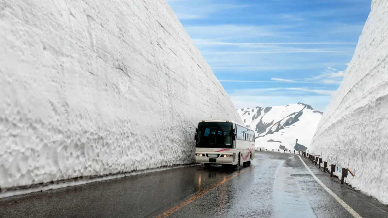 snow wall at kurobe alpine in japan with bus for