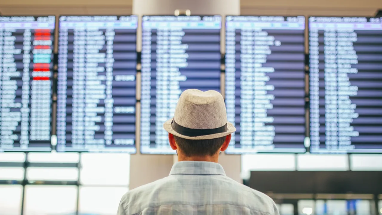 solo traveler man standing inside airport terminal looking at