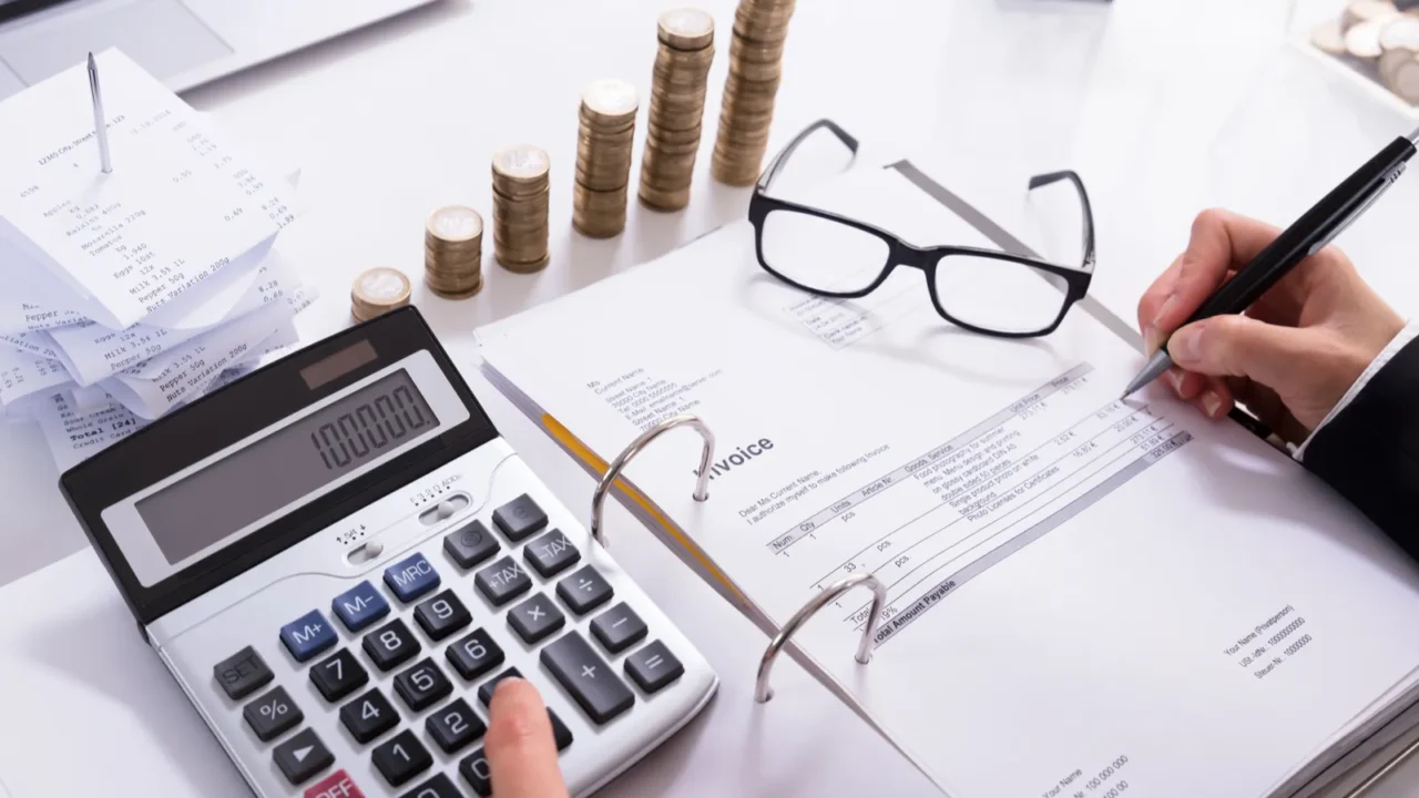 stacked coins and laptop in front of businesswoman calculating invoice