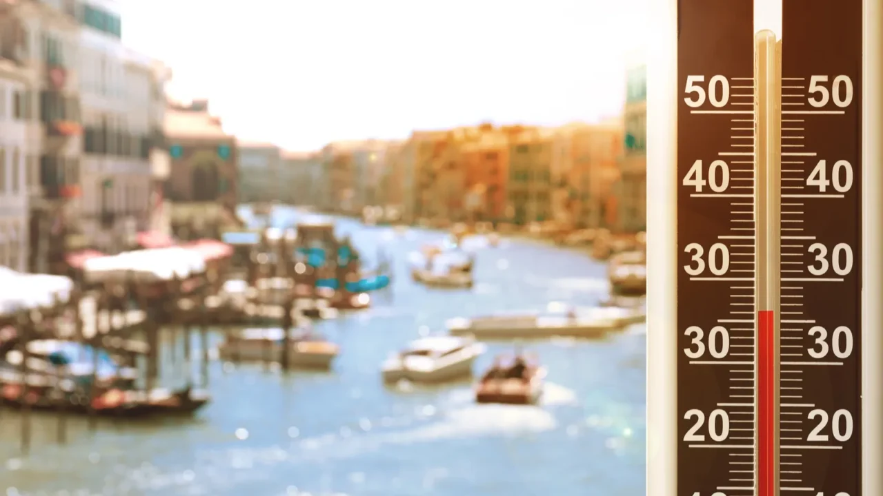 thermometer showing high temperature against city during hot day