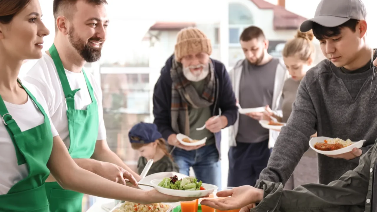volunteers giving food to poor people indoors