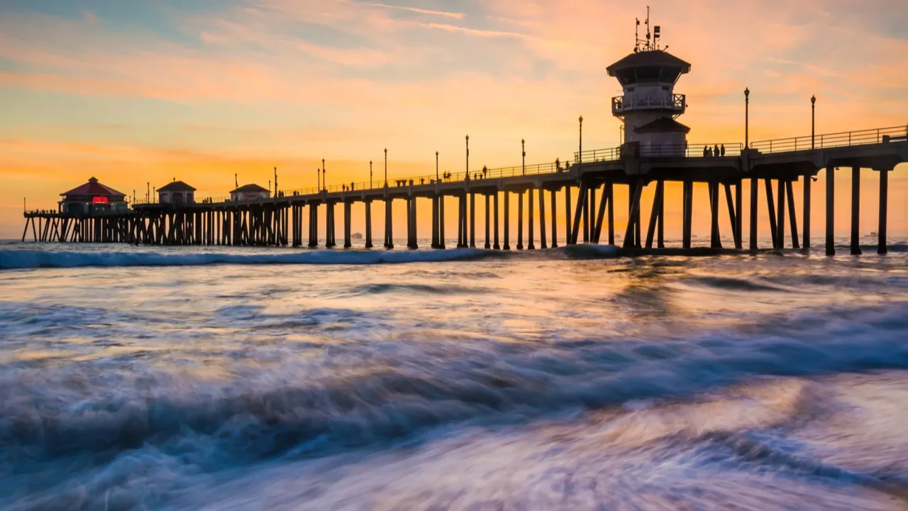 waves in the pacific ocean and the pier at sunset