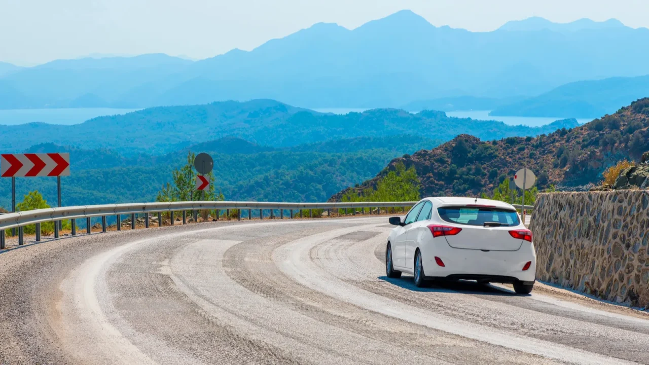 white car in turn a mountain road