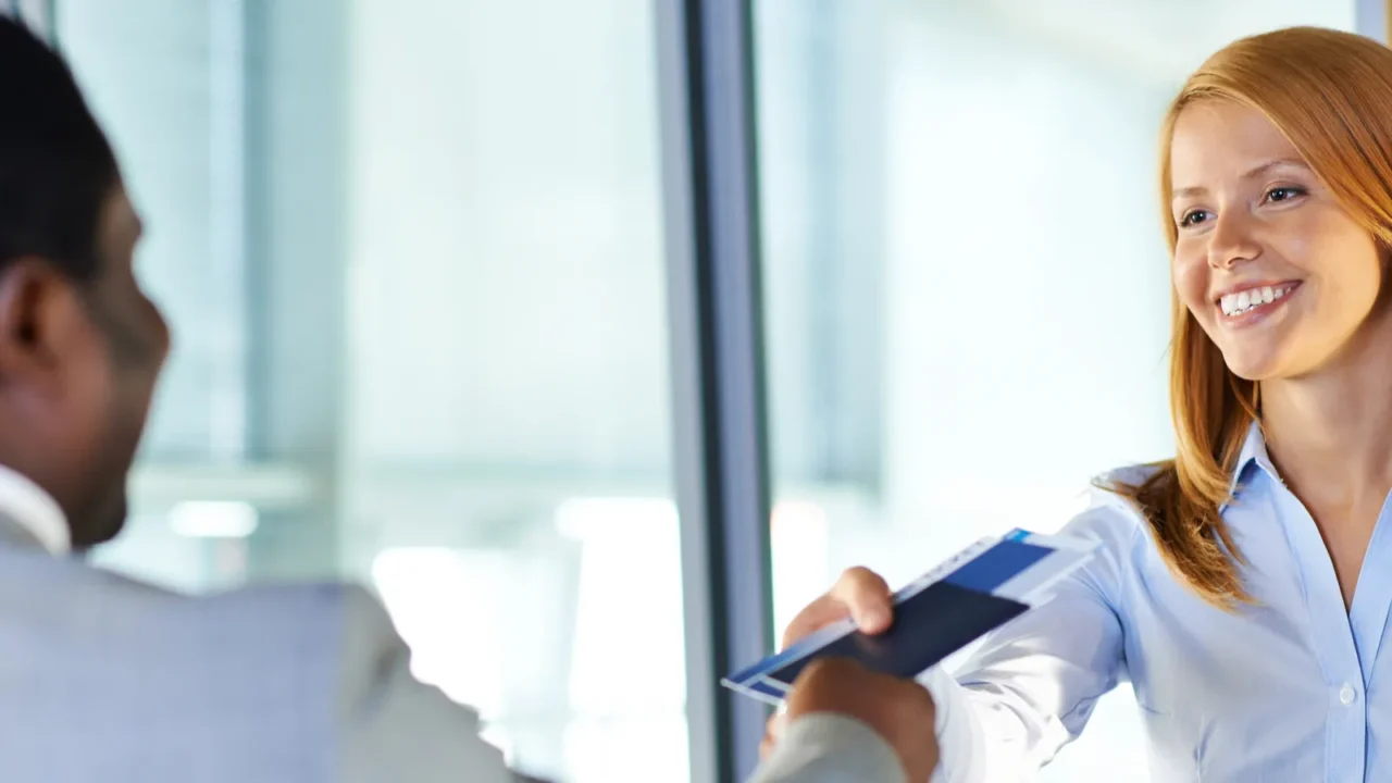 woman giving passport and ticket to businessman at airport