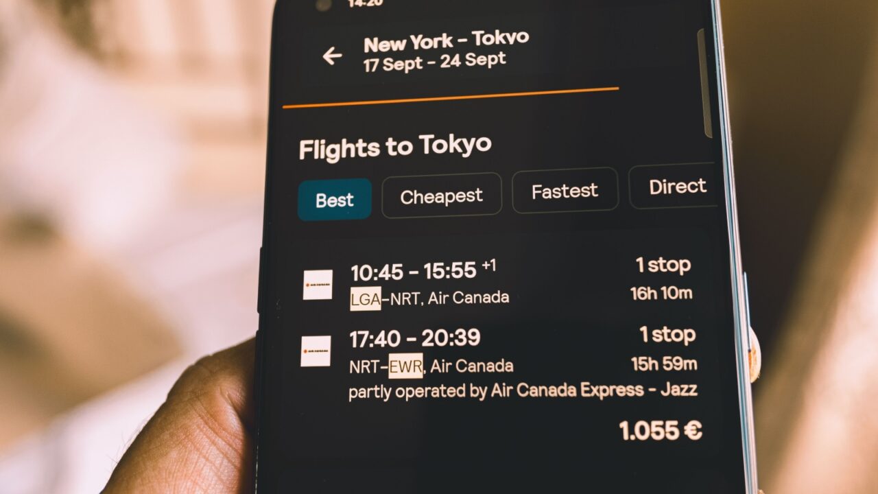 madrid, spain 28-10-2024: looking for flight tickets to Tokyo from New York on mobile phone