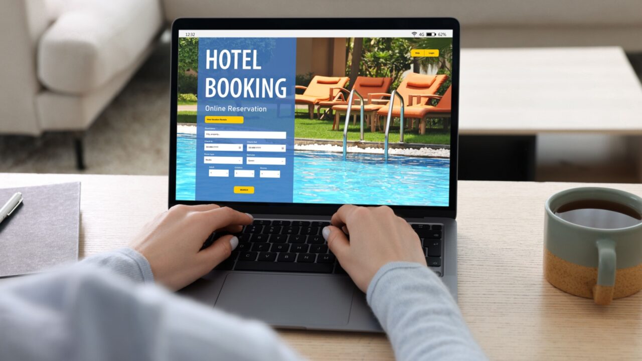 Woman using laptop to book hotel at wooden table, closeup