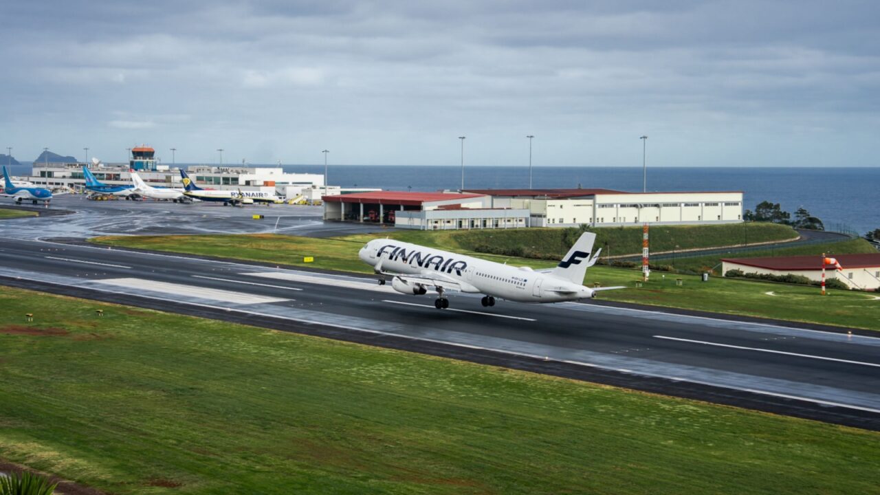 Madeira, Portugal. May 5, 2025. A Finnair Airbus touches down on a wet runway at Cristiano Ronaldo Madeira International Airport in Funchal, with the Atlantic, control tower and a Ryanair jet visible.