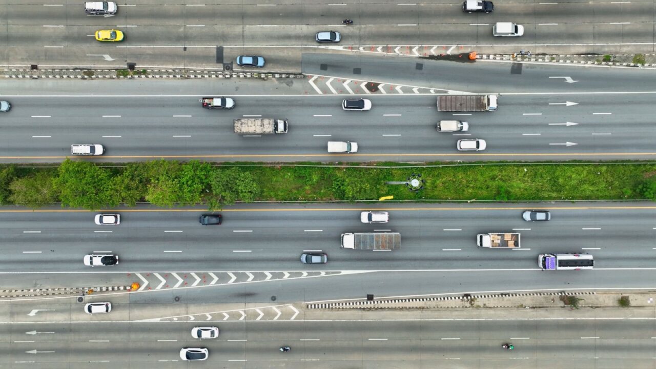 An aerial canvas reveals the intricate patterns of urban travel. Cars, buses, and a solitary motorcyclist form a colorful mosaic as they traverse the marked lanes, painting the road with motion.
