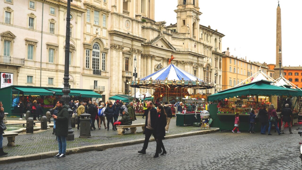 Rome, December 08, 2022: Tourists near the equestrian carousel in Piazza Navona with the traditional Christmas Market in Rome, back after years with the stalls with games, gadgets and typical food