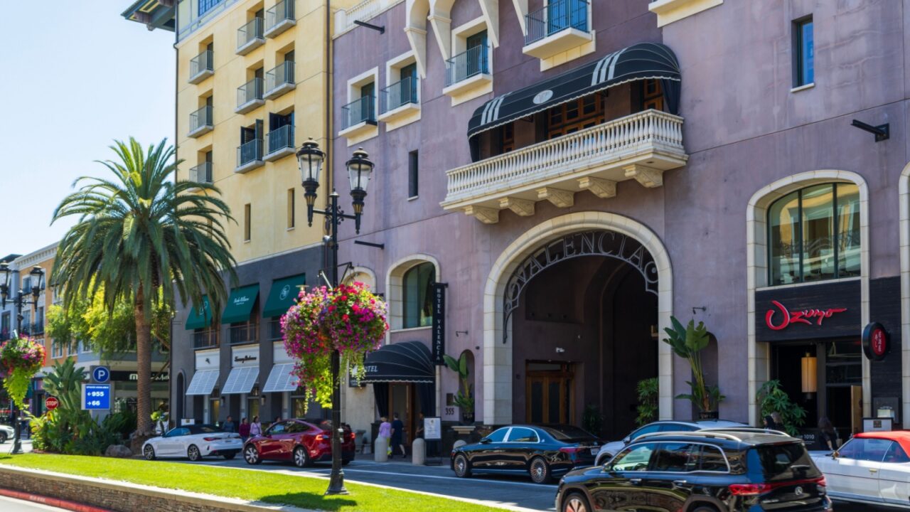 San Jose California USA - 7 15 2025: a hotel, restaurants, parked cars, palm trees, and ornate streetlights on a bright day at Santana Row Shopping Mall in San Jose California USA