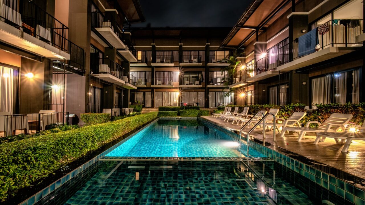 long exposure night shot image of resort pool and resort building in condominium style with swimming pool and pool chairs along pool side at Lalune beach resort Samed island Rayong Thailand