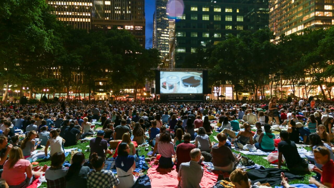 NEW YORK, USA – JUNE 2013: Crowds gather on the lawn for the Bryant Park Summer Film Festival, a free outdoor movie screening in Midtown Manhattan surrounded by skyscrapers.