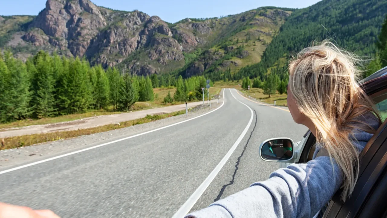 a blonde woman with her head out the window enjoying