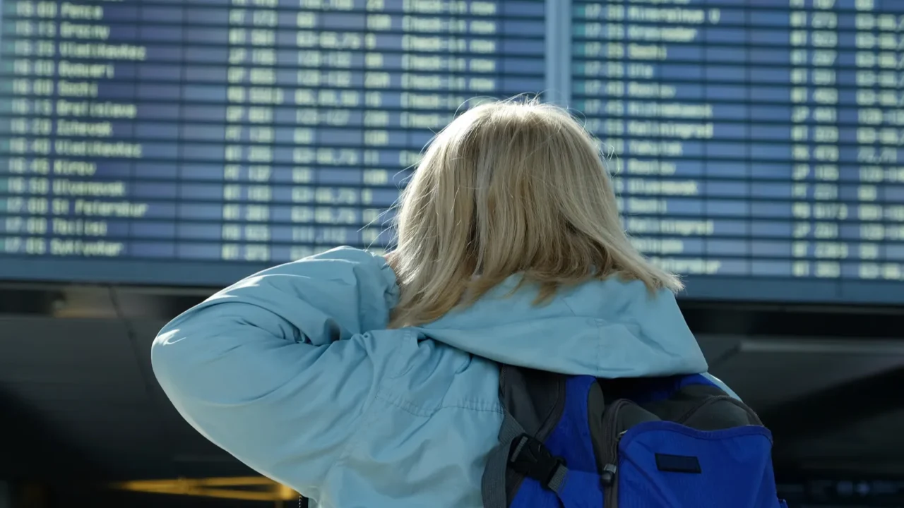 a woman with a backpack looks at departure board