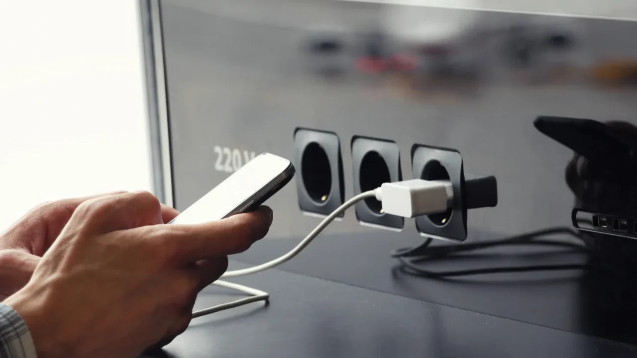 airport public charger and mans hands with smartphone airplane in