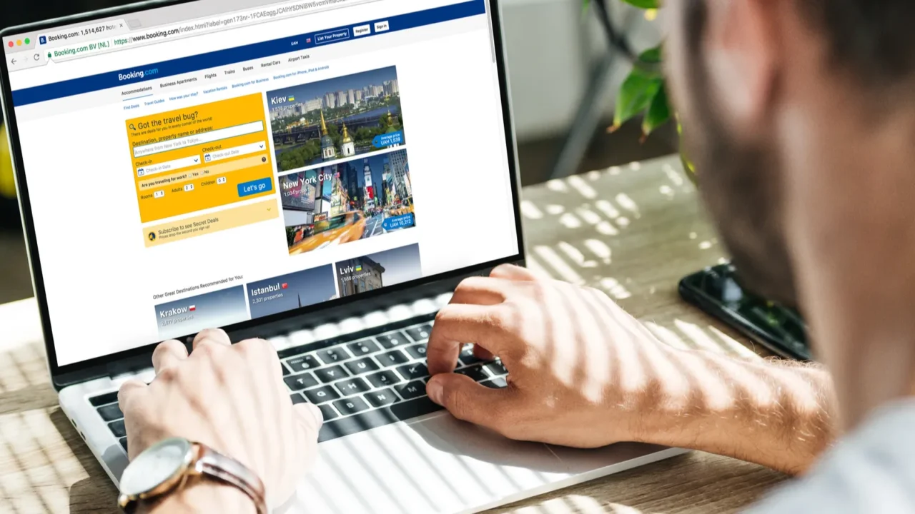 back view of man using laptop with booking website on