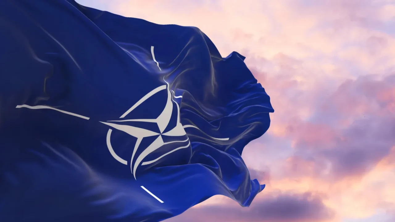 flag of nato waving in the wind on flagpole against