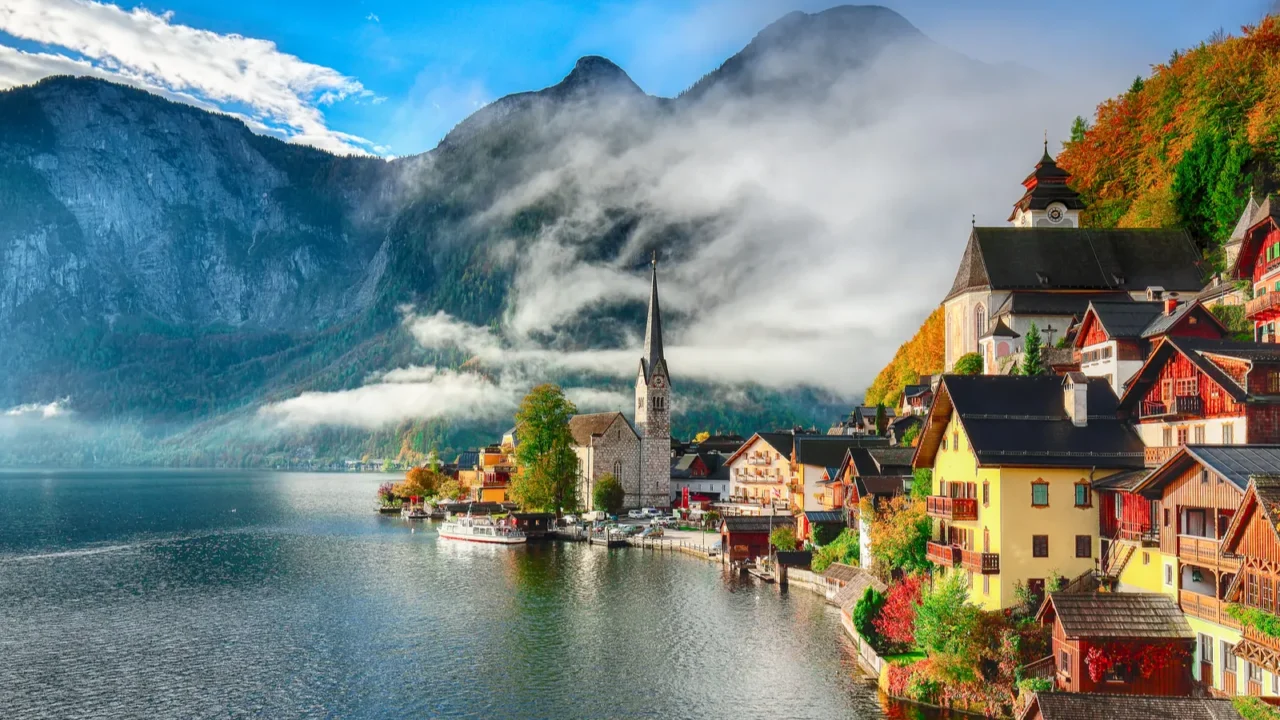 foggy autumnal sunrise at famous hallstatt lakeside town reflecting in