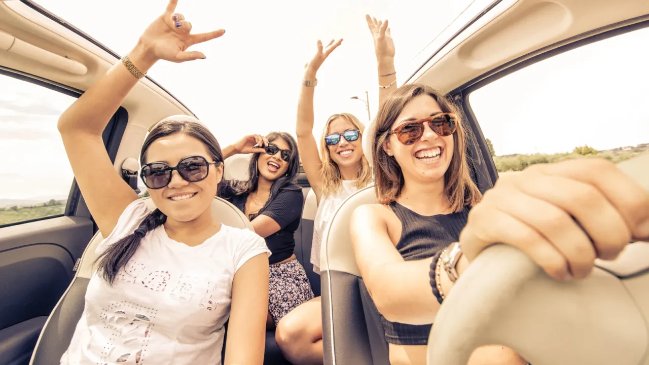four girls driving in a convertible car and having fun