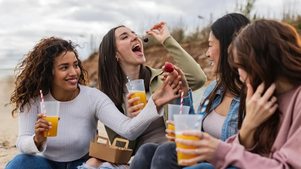 friends having a snack on the beach eating fruit and