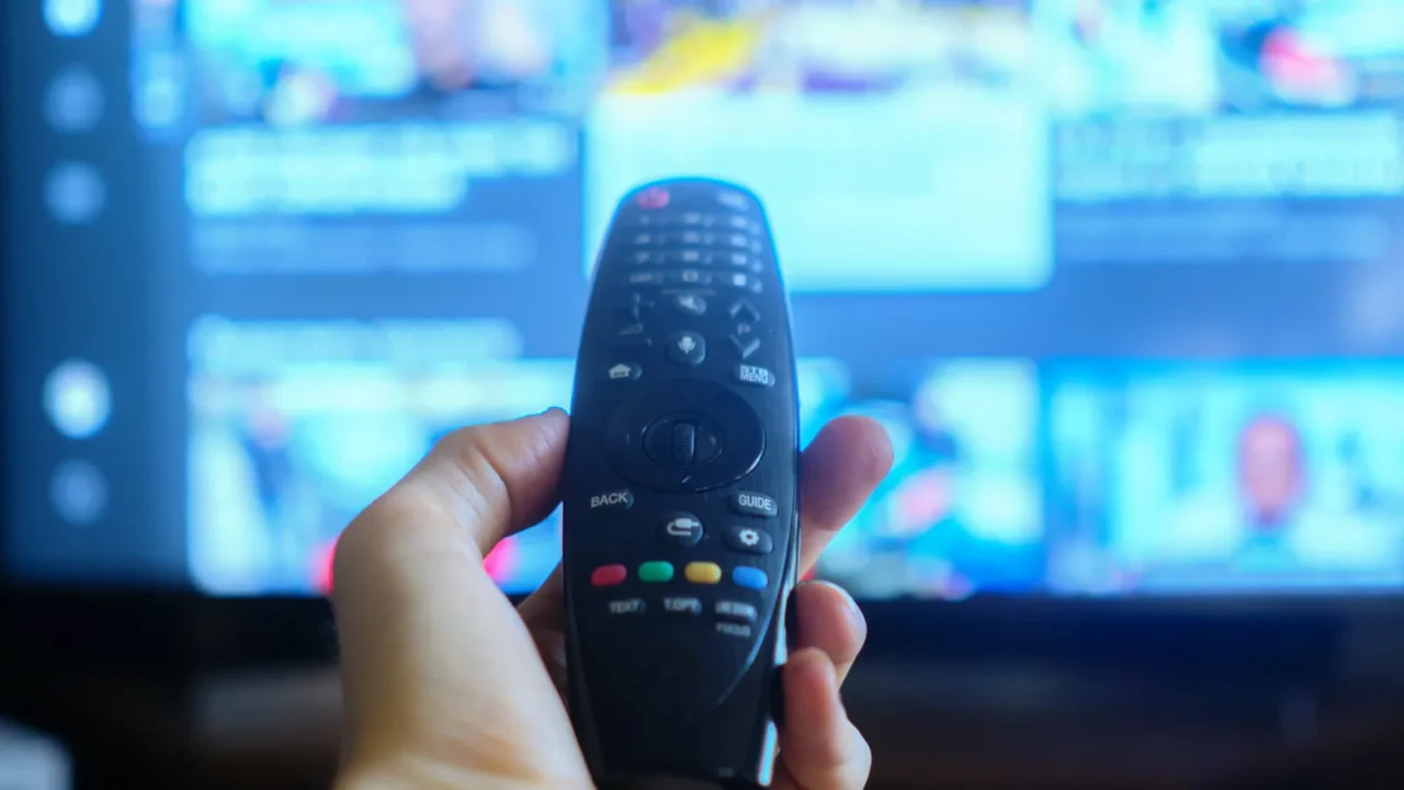 hand holding a tv remote swithing media chanels screens