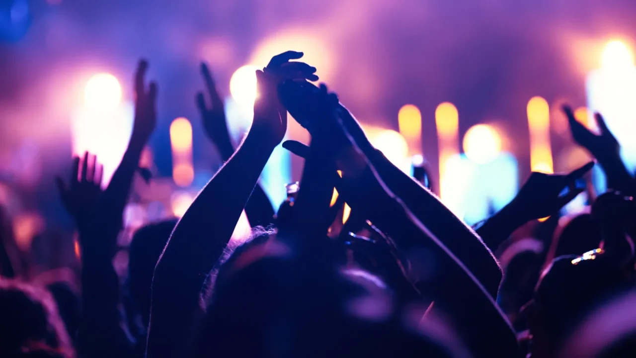 happy cheering crowd with hands in air at music festival