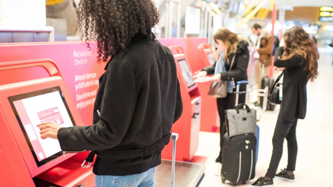 happy woman using the checkin machine at the airport getting
