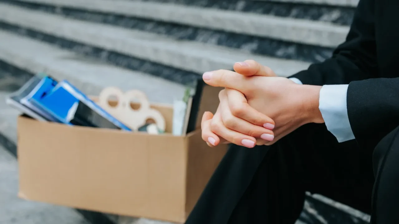 human hands clutching a carton box representing job loss and