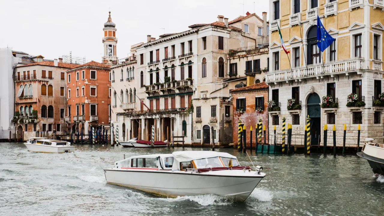 motor boats floating on canal near ancient buildings in venice