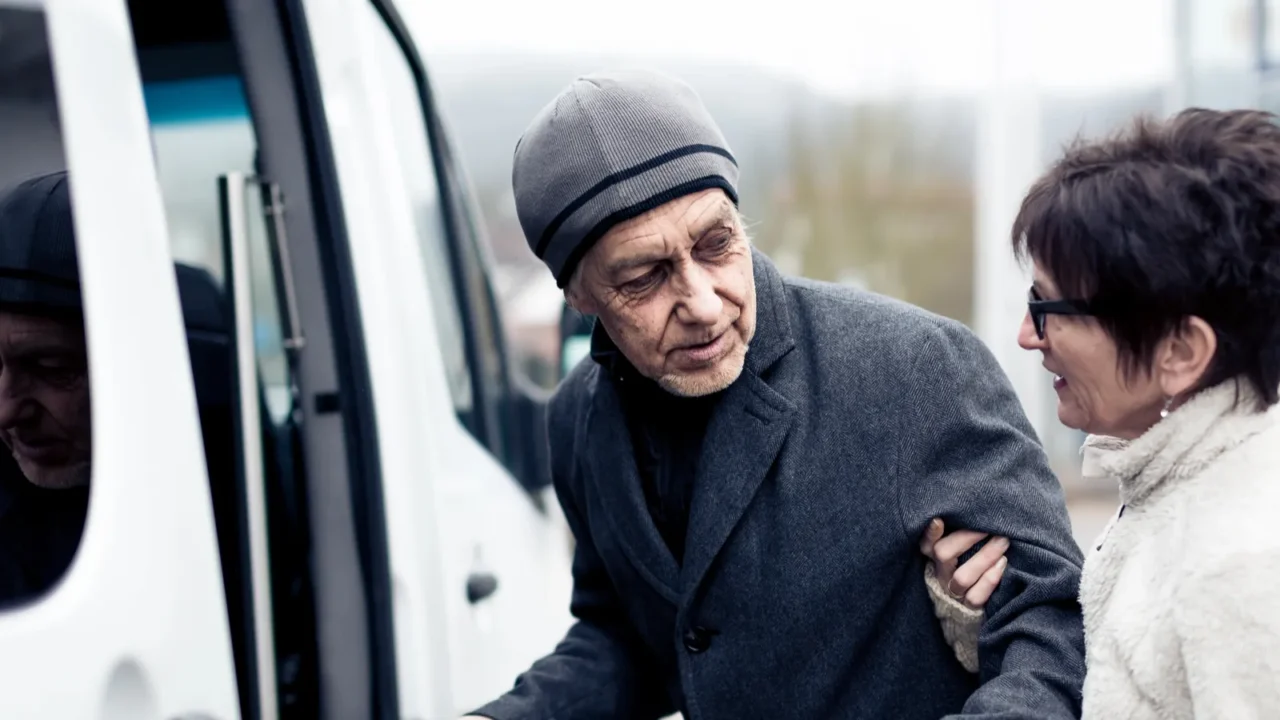 nurse helping senior man enter a van