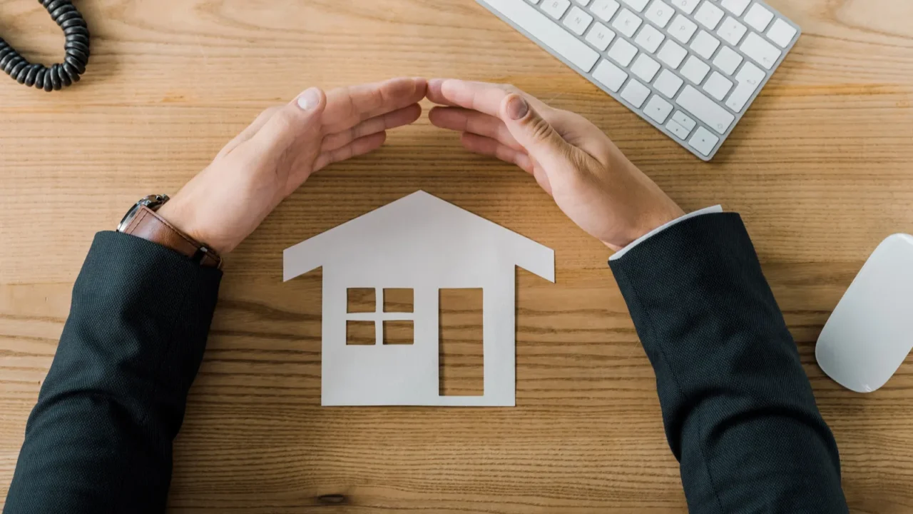 partial view of businessman covering house paper model with hands