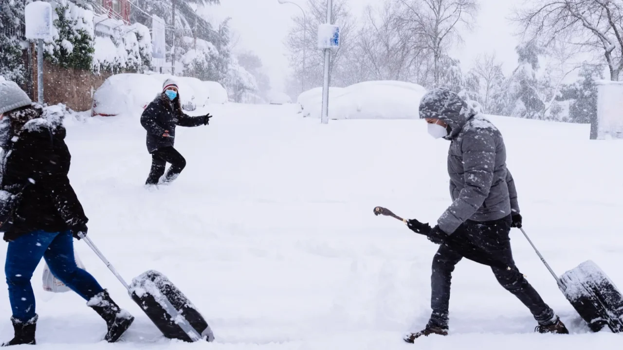 people carrying trolleys on a city street covered in snow