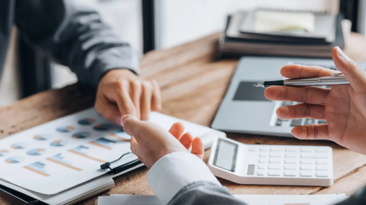 two businessmen are reviewing monthly sales documents for analysis and