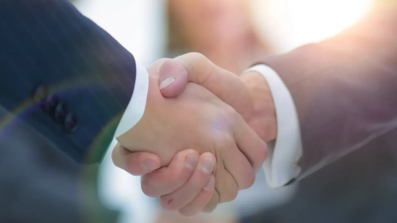 two businessmen shaking hands with colleagues on background