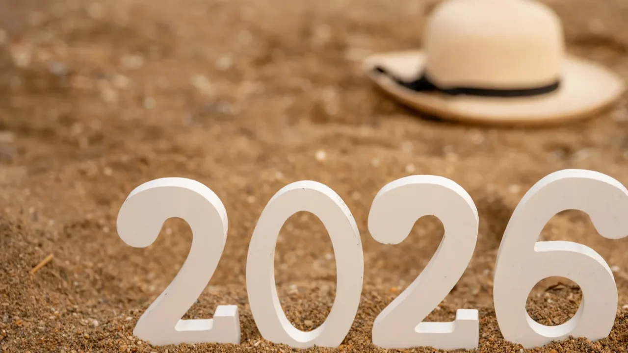 white wooden numbers 2026 standing on golden sand beach with