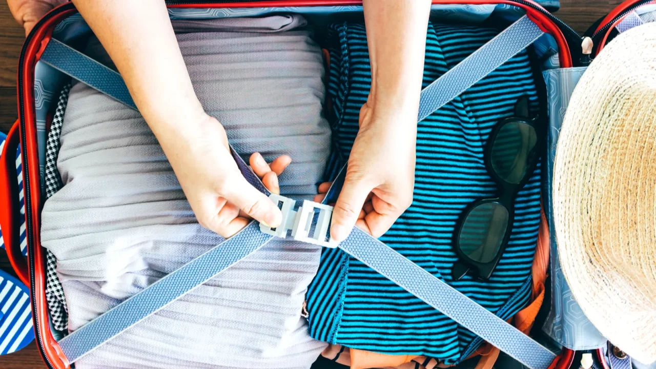 woman packing a luggage on wooden floor