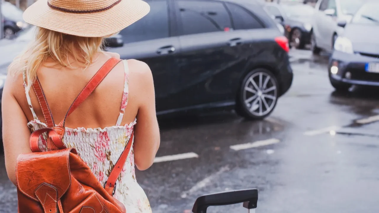 woman waiting for taxi tourist commuter with suitcase and backpack