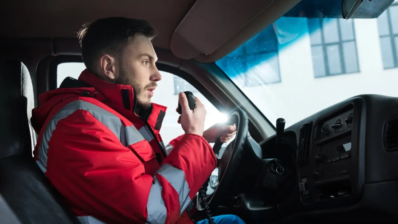 young handsome male paramedic talking by portable radio