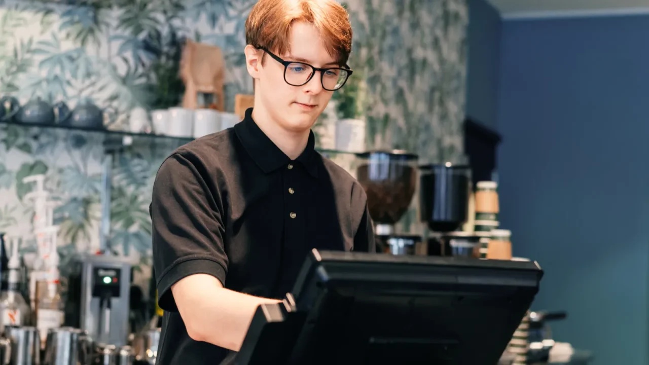young waiter serving customer at cash point in cafe man