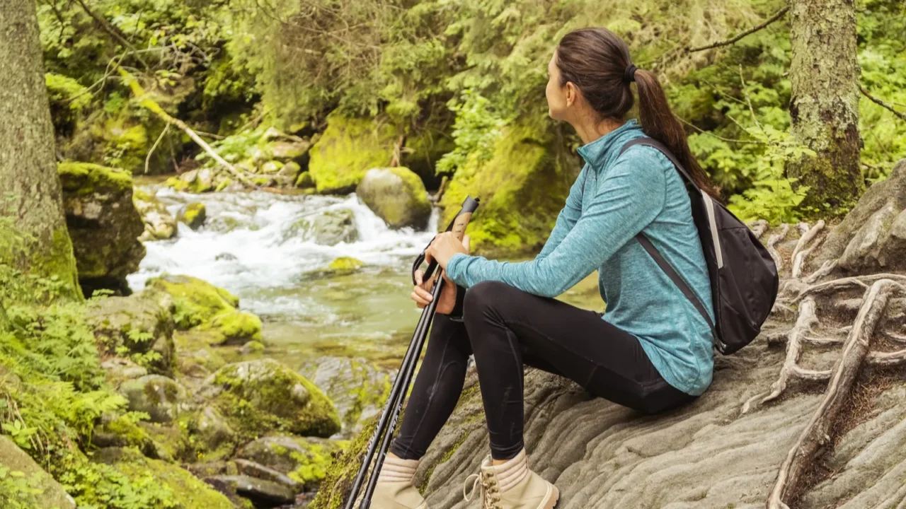 young woman is trekking around the mountains and admires a