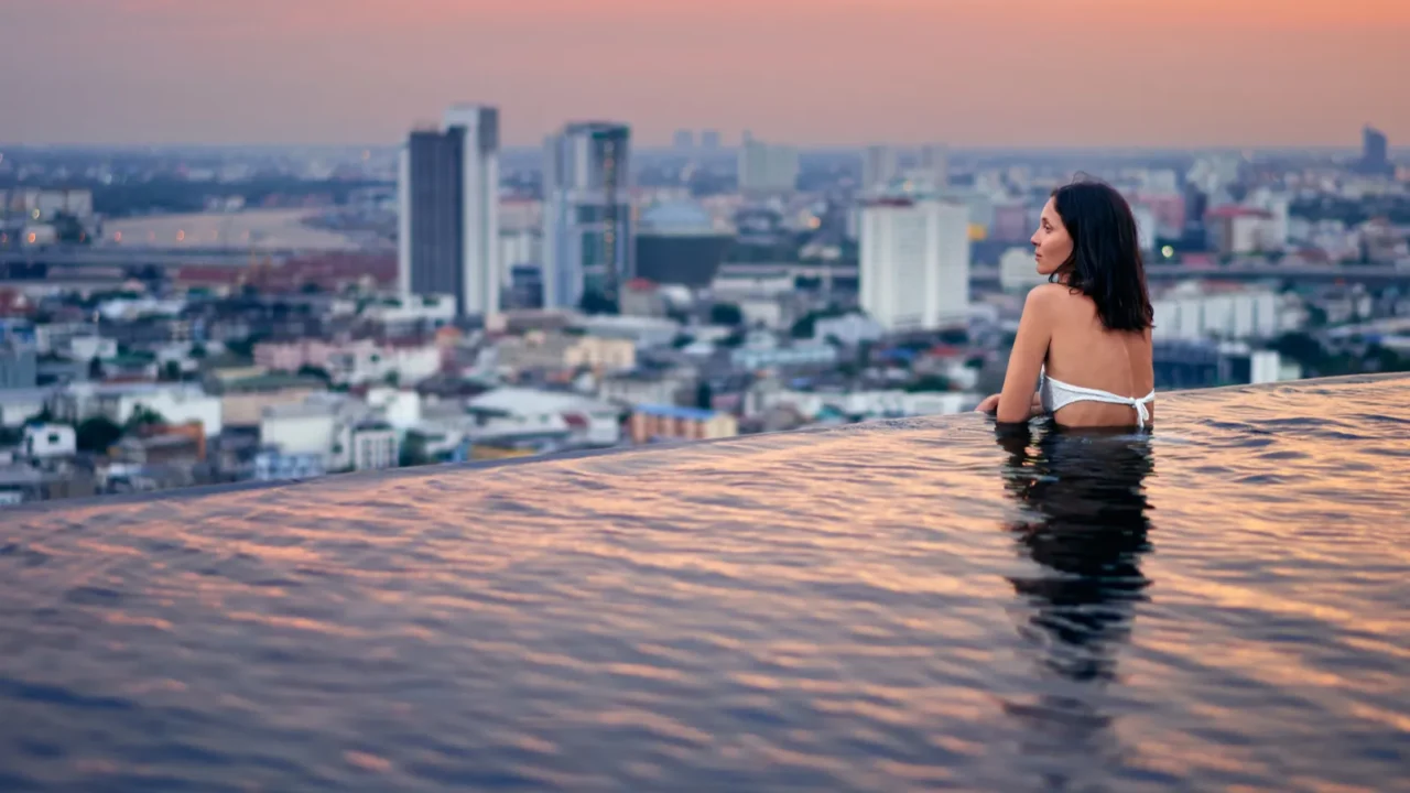 young woman relaxing in swimming pool on roof top during