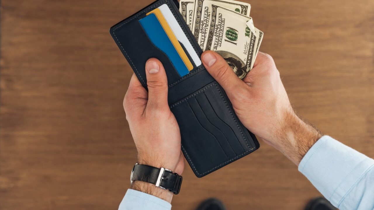 top view of man puting dollars banknotes in wallet with