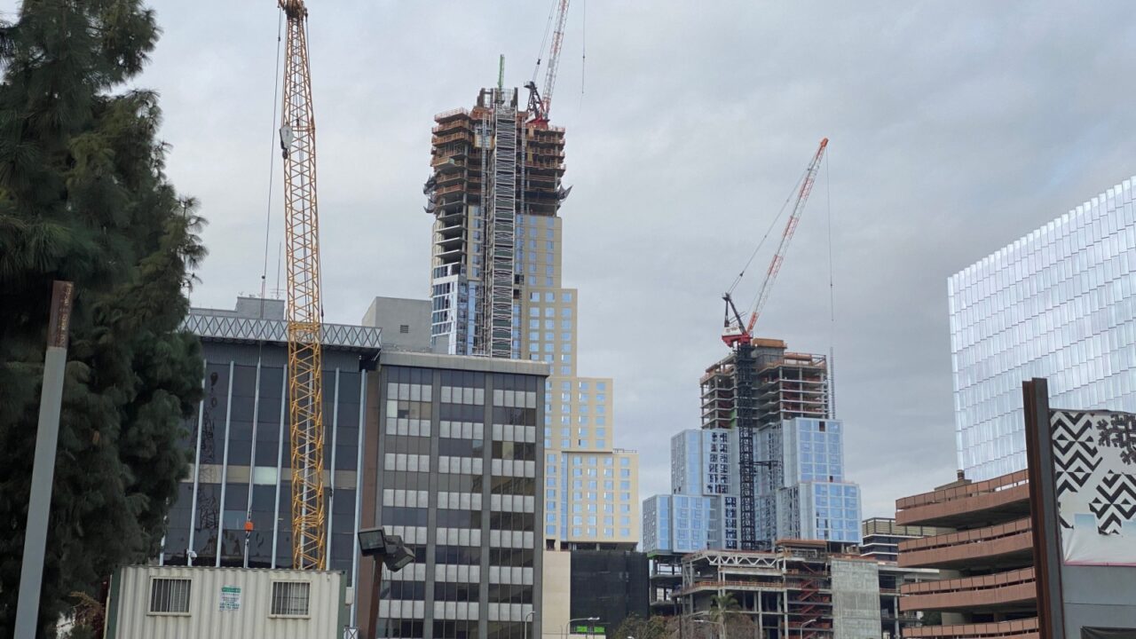 LOS ANGELES, CA, JAN 2021: construction cranes working in Downtown, with new rail transit link in foreground and Frank Gehry designed building behind