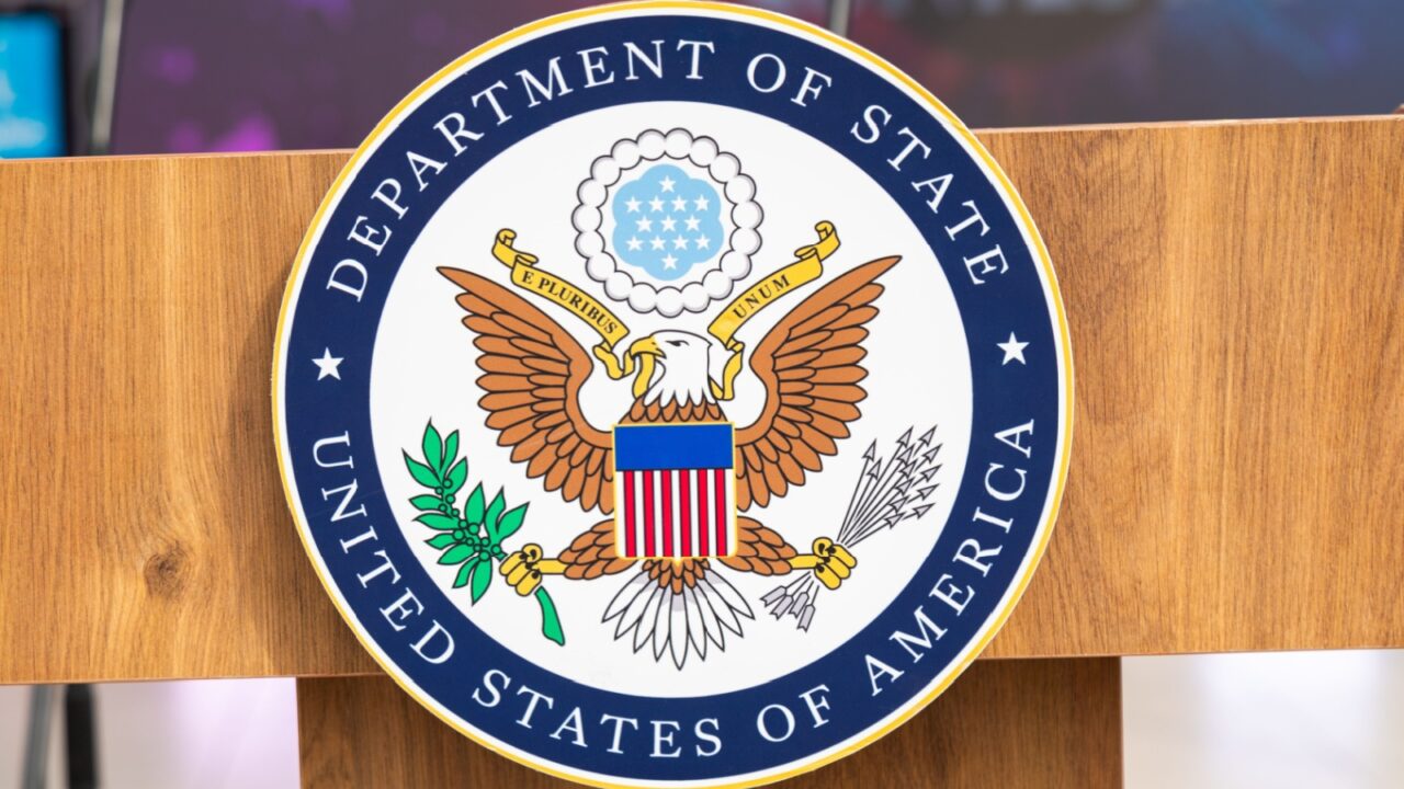 Close-up of the United States Department of State seal on a wooden podium with a blurred background