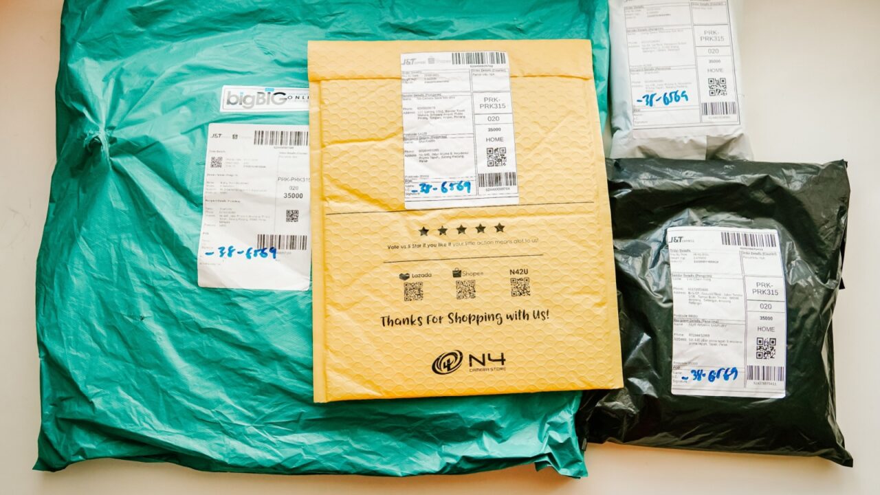 Tapah, Perak - Feb 2021 : Packaging items of different colors on a white table. each package has a label with info on the sender, receiver and service provider.