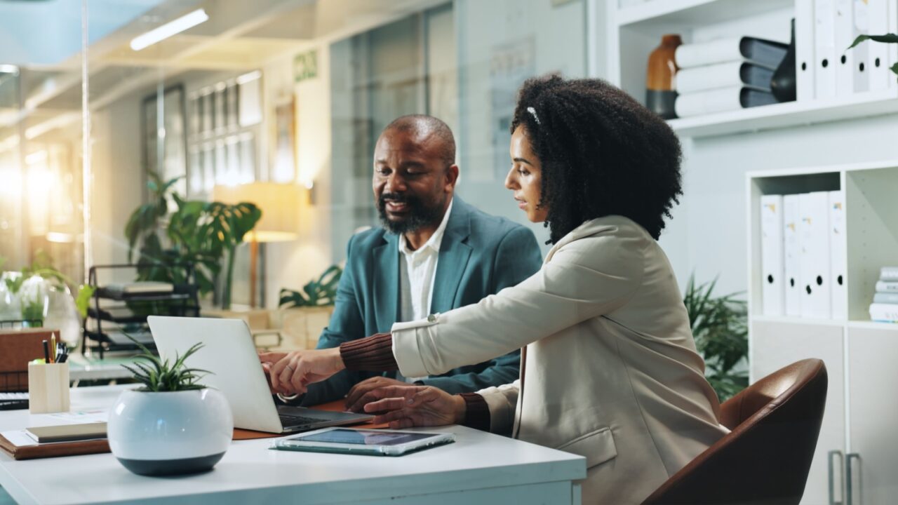 Laptop, business people and team planning in office for insurance, meeting or idea at night. Computer, collaboration and happy African workers with feedback, solution and help with policy on overtime