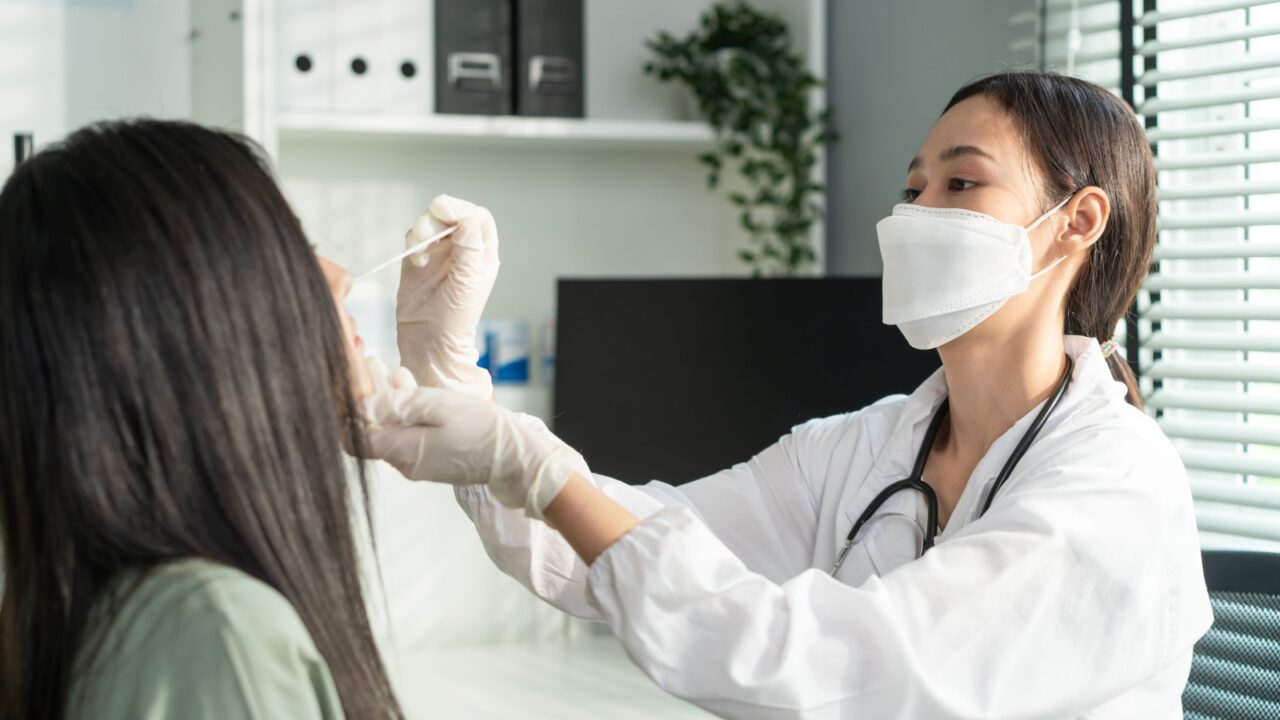 Close up of Asian specialist doctor diagnosis PCR Coronavirus sample. Young researcher using a rapid antigen test doing quick swab for patient during Covid 19 pandemic in medical laboratory hospital.